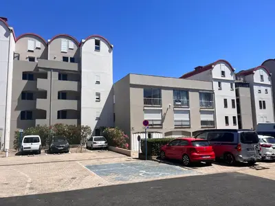 a parking lot with cars parked in front of a building at L'appart D79 in Gruissan