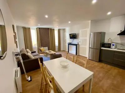 a living room with a white table and a kitchen at Chez Isa et Thomas in Narbonne