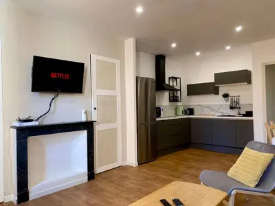 a living room with a television and a kitchen at Chez Isa et Thomas in Narbonne