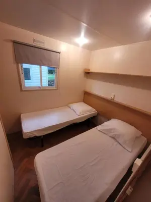 a small room with two beds and a window at Camping du Bois Fleuri in Fontiers-Cabardès