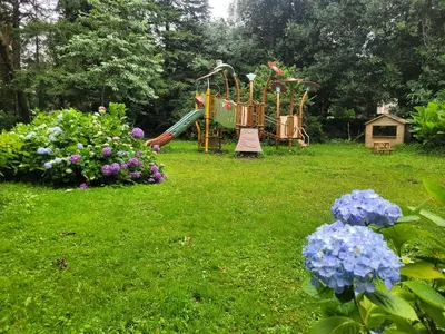 a garden with a playground and flowers in the grass at Camping du Bois Fleuri in Fontiers-Cabardès