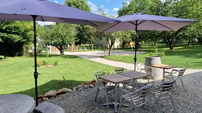 two tables and chairs with umbrellas in a park at Dortoir Gîte d'étapes 