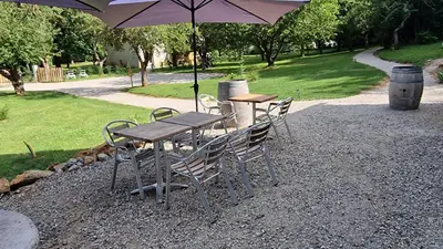 a wooden table and chairs with an umbrella at Dortoir Gîte d'étapes 
