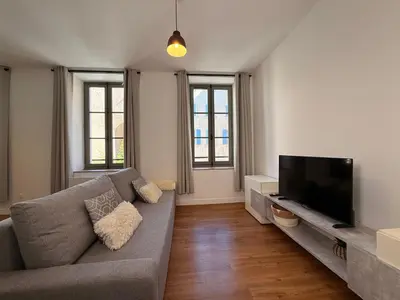 a living room with a couch and a flat screen tv at Le Moderniste Proche des Halles et Cathédrale in Narbonne