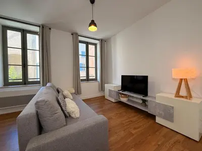 a living room with a couch and a tv at Le Moderniste Proche des Halles et Cathédrale in Narbonne