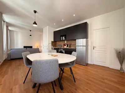 a kitchen and living room with a table and chairs at Le Moderniste Proche des Halles et Cathédrale in Narbonne