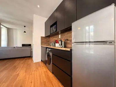 a kitchen with black cabinets and a stainless steel refrigerator at Le Moderniste Proche des Halles et Cathédrale in Narbonne