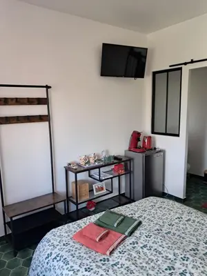 a bedroom with a bed and a tv on the wall at Gentil coquelicot in Mirepoix