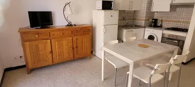 a small kitchen with a table and a refrigerator at Superb T2 near the beach of Port-la-Nouvelle in Port-la-Nouvelle