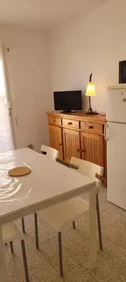 a white table and chairs in a kitchen with a refrigerator at Superb T2 near the beach of Port-la-Nouvelle in Port-la-Nouvelle