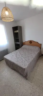 a bedroom with a bed and a cabinet and a lamp at Superb T2 near the beach of Port-la-Nouvelle in Port-la-Nouvelle
