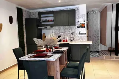 a kitchen with green cabinets and a table with chairs at T3 6 couchages grands buffets et plages in Narbonne