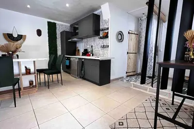 a kitchen with black cabinets and a white tile floor at T3 6 couchages grands buffets et plages in Narbonne