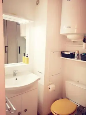 a white bathroom with a sink and a toilet at Appartement 600M de la plage in Port-la-Nouvelle