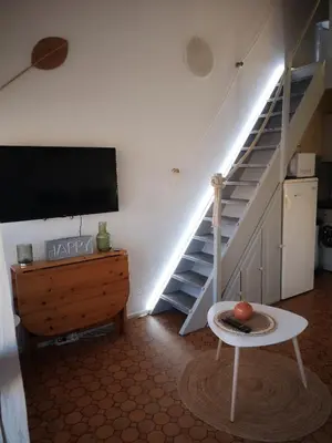 a living room with a tv and a staircase at Appartement 600M de la plage in Port-la-Nouvelle