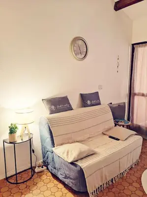 a bed in a room with a clock on the wall at Appartement 600M de la plage in Port-la-Nouvelle