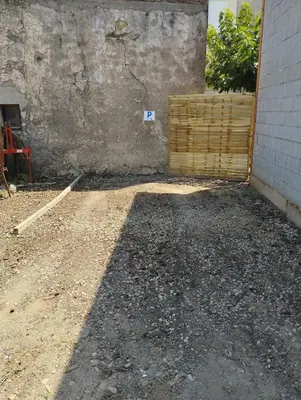 a dirt yard with a wall and a building at Entre canal et garrigue in Roubia