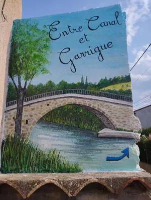 a painting of a bridge on the side of a building at Entre canal et garrigue in Roubia