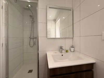 a white bathroom with a sink and a shower at Le Saint Just T2 proche des Halles Wifi in Narbonne