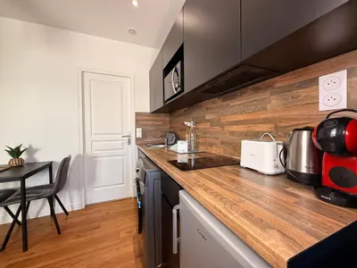 a kitchen with a wooden counter top and a table at Le Saint Just T2 proche des Halles Wifi in Narbonne
