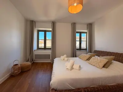 a bedroom with a large white bed with towels on it at Le Saint Just T2 proche des Halles Wifi in Narbonne