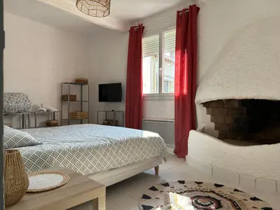 a bedroom with a bed and a window with red curtains at Spacieux T2 climatisé Narbonne - Près du centre ville in Narbonne