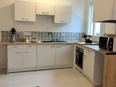 a kitchen with white cabinets and white appliances at Spacieux T2 climatisé Narbonne - Près du centre ville in Narbonne