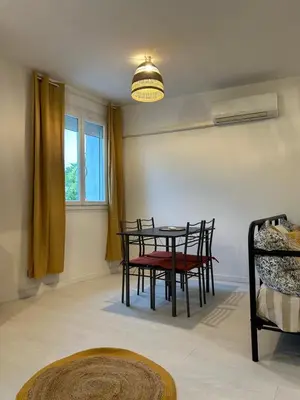 a dining room with a table and chairs and a window at Spacieux T2 climatisé Narbonne - Près du centre ville in Narbonne