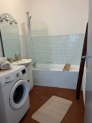 a bathroom with a washing machine and a bath tub at Spacieux T2 climatisé Narbonne - Près du centre ville in Narbonne