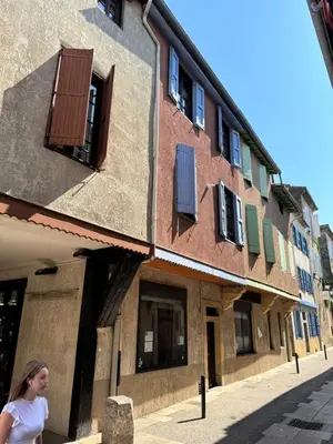 a woman walking in front of a building at Chambre Lits Jumeaux in Mirepoix