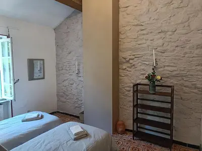 a bedroom with two beds and a stone wall at Ceps Cottage sleeps 6 with free wifi near the river in Roquebrun