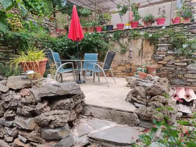 a patio with a table and chairs and a stone wall at Ceps Cottage sleeps 6 with free wifi near the river in Roquebrun