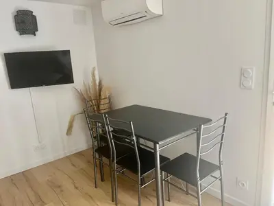 a dining room table with chairs and a television at Charmant et Confortable appartement Narbonne in Narbonne