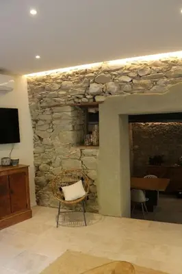 a living room with a stone fireplace and a chair at L'Echauguette, villa de luxe avec piscine au pied de la Cité in Carcassonne