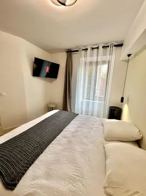 a bedroom with a bed and a tv on the wall at Le Margaux Balnéo spacieux calme in Conques-sur-Orbiel