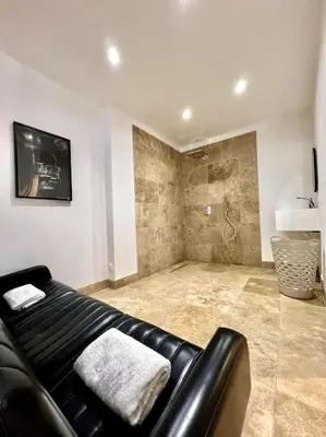 a living room with a black leather couch and a tv at Le Margaux Balnéo spacieux calme in Conques-sur-Orbiel
