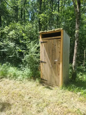 a wooden outhouse sitting in the middle of a field at Bulle perchée in Sonnac-sur-lʼHers