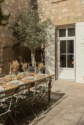 a wooden table with chairs in front of a building at Maison Esme - Charm & Authenticity in Salles-d'Aude