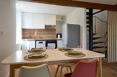 a kitchen with a table with chairs and a refrigerator at Le Rempart Harmonieux - Triplex au pied de la Cité in Carcassonne