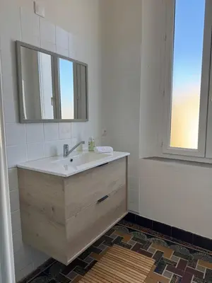 a bathroom with a sink and a mirror and a window at La maison de la gare in Carcassonne