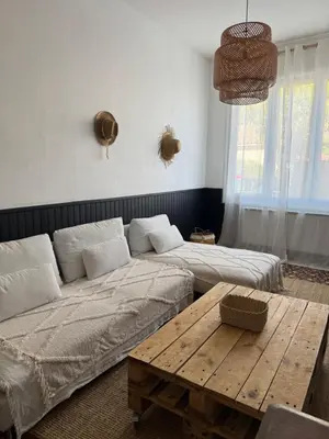 a living room with two beds and a wooden table at La maison de la gare in Carcassonne