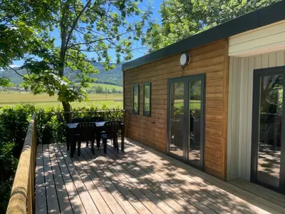 a deck with a table and chairs on a house at Camping du lac Fontclaire in Puivert