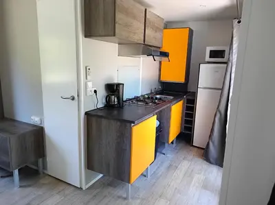 a small kitchen with a stove and a refrigerator at Camping du lac Fontclaire in Puivert