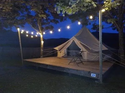 a tent on a wooden platform under a tree at night at Camping du lac Fontclaire in Puivert