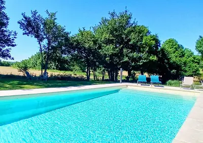 a swimming pool with two blue chairs and trees at La petite maison de Valérie proche château de la Rode, du Domaine de Flore et du Lac Saint Ferréol in Lempaut