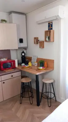 a small kitchen with a table and stools in it at Studio Valliere les halles 15m2 avec clim in Narbonne