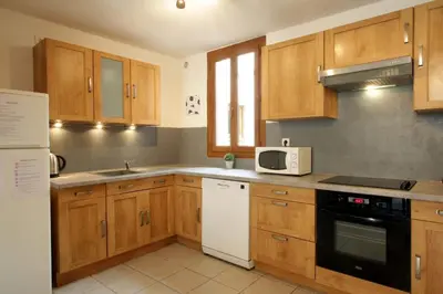 a kitchen with wooden cabinets and a white microwave at Résidence Armagnac - City Center in Carcassonne