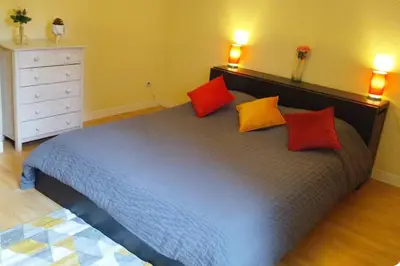 a bedroom with a large bed with red and yellow pillows at Résidence Armagnac - City Center in Carcassonne