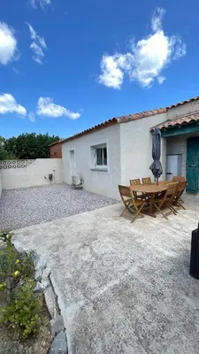 a patio with a table and chairs and a building at Villa familiale climatisée, proche plage & lacs in Port-la-Nouvelle