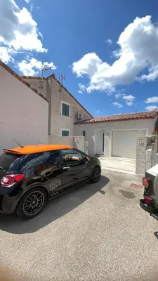 a car with a surfboard on the roof parked in a driveway at Villa familiale climatisée, proche plage & lacs in Port-la-Nouvelle